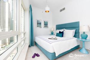 a bedroom with a blue and white bed and a window at Dream Inn Apartments - Al Sahab in Dubai