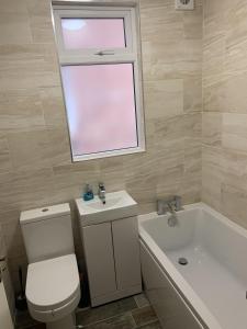 een badkamer met een toilet, een wastafel en een raam bij Entire Seaside Home, Sleeps 8, All en-suite rooms in New Brighton