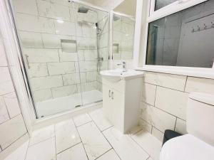 a white bathroom with a shower and a sink at Leytonstone House - SleepyLodge in London