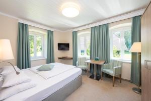 una camera con letto, scrivania e finestre di Inselhotel Faakersee a Faak am See