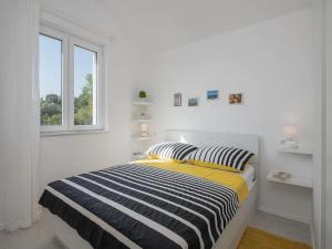 een witte slaapkamer met een bed met gestreepte kussens bij Apartment Dolce in Cavtat
