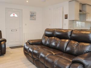 a brown leather couch sitting in a living room at Bankswood in Dumfries