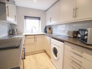 a kitchen with white cabinets and a washer and dryer at Bankswood in Dumfries