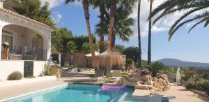 ein Pool neben einem Haus mit Palmen in der Unterkunft Casa Bonita in Benissa