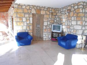 a living room with two blue chairs and a tv at Ville Alba & Azzurra in Polignano a Mare