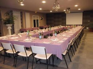 uma longa mesa de banquete com pano de mesa roxo e cadeiras em Kyriad Auxerre Appoigny em Appoigny