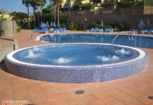 a large swimming pool with a tiled floor and chairs at Bungalow Bahia Meloneras in Maspalomas