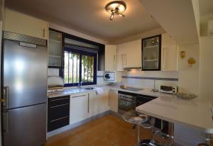 a kitchen with white cabinets and a stainless steel refrigerator at Bungalow Bahia Meloneras in Maspalomas