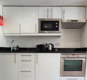 a kitchen with a microwave, oven, sink, and dishwasher at Hyde Park Superior Apartments in London