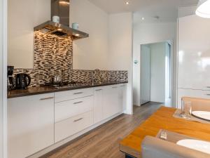 una cucina con mobili bianchi e un tavolo di legno di Holiday Home Green Resort Mooi Bemelen-1 by Interhome a Bemelen