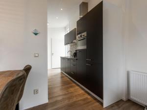 a kitchen with black cabinets and a wooden table at Holiday Home Biebosch by Interhome in Bemelen +10 photos