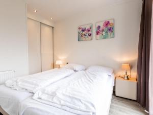 ein weißes Bett in einem Schlafzimmer mit zwei Bildern an der Wand in der Unterkunft Holiday Home Green Resort Mooi Bemelen by Interhome in Bemelen