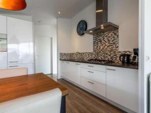 a kitchen with white cabinets and a clock on the wall at Holiday Home Green Resort Mooi Bemelen by Interhome in Bemelen