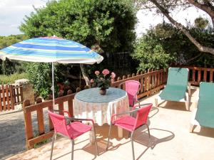 a table with chairs and an umbrella on a patio at Holiday Home Sa Caseta by Interhome in Cala Santanyi