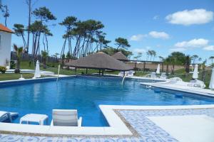 una piscina con sillas y sombrillas en un complejo en Palmeras Beach Hotel, en Punta del Este