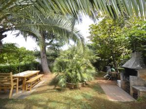 un jardín con una mesa, bancos y una palmera en Apartment Denise - MDN125 by Interhome, en Medulin