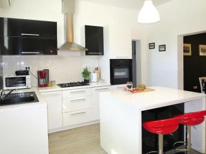 a kitchen with white cabinets and red bar stools at Holiday Home Dordana - LBN440 by Interhome in Labin