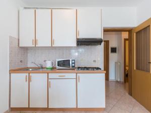 a kitchen with white cabinets and a sink and a microwave at Apartment Adria - RAC171 by Interhome in Rabac