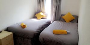 two beds in a small room with yellow pillows at Bel Reve Hotel in Blackpool