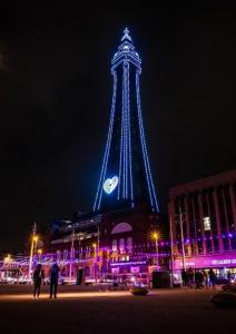 a tower lit up at night with a clock on it at Bel Reve Hotel in Blackpool +9 photos