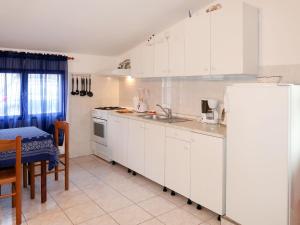 cocina con armarios blancos y nevera blanca en Apartment Haus Peric - KOR201 by Interhome en Prigradica
