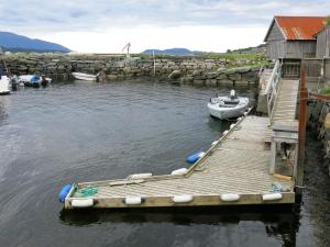 un muelle con un pequeño barco sobre un cuerpo de agua en Apartment Mjellhaugen - FJS221 by Interhome, en Naustdal i Sunnfjord