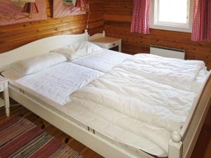 ein großes weißes Bett in einem Schlafzimmer mit Holzwänden in der Unterkunft Chalet Fjellro - FJS103 by Interhome in Holsen