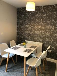 a dining room with a table and chairs and a wall with writing at Hill House - 5 Mins Merry Hill - Perfect for Contractors & Families in Brettell Lane +8 photos