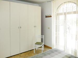 a bedroom with white cabinets and a chair next to a window at Holiday Home Gabriele by Interhome in Picciano