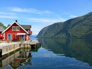a red house on a dock on a body of water at Apartment Fagerdalsnipi - FJS609 by Interhome in Arnefjord
