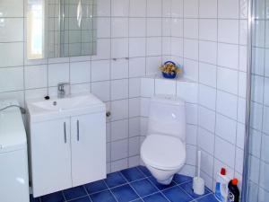 a white tiled bathroom with a toilet and a sink at Apartment Fagerdalsnipi - FJS609 by Interhome in Arnefjord