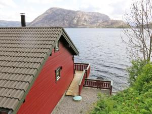 une maison rouge avec un escalier en bois à côté d'une masse d'eau dans l'établissement Holiday Home Idun - FJS131 by Interhome, à Hyllestad