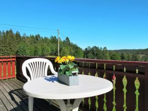 a white table and chair on a deck with flowers at Chalet Espetveit by Interhome in Hornnes