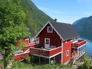 ein rotes Haus am Ufer eines Sees in der Unterkunft Holiday Home Heimdall - FJS604 by Interhome in Arnefjord