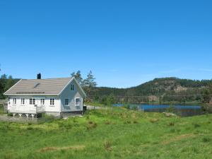 uma casa branca num campo ao lado de um lago em Holiday Home Der ute - SOW441 by Interhome em Brådland