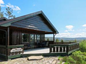 a log cabin with a deck and a patio at Holiday Home Skafjellstoga by Interhome in Åmli