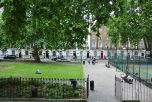 un parque con gente sentada en el césped frente a un edificio en European Hotel, en Londres