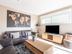 ein Wohnzimmer mit einem Sofa und einem Flachbild-TV in der Unterkunft Holiday Home Blue House - BAY403 by Interhome in Bretteville-sur-Ay