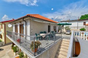 a balcony of a house with chairs and an umbrella at TOMIC A MAZURANICA in Novi Vinodolski
