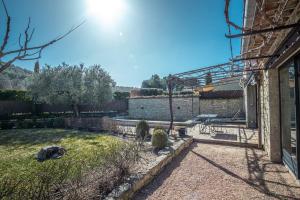 Un jardín con un muro de piedra y un patio. en Gîte tout confort - jardin et piscine chauffée, en Lagnes