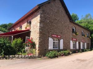 a brick building with flowers in front of it at La Vieille Auberge du Lac in Saint-Agnan