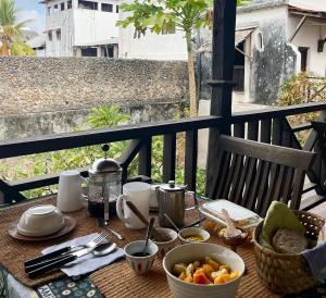a table with a bowl of fruit on a balcony at Subira House in Lamu +64 photos