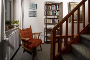 eine Treppe mit einem Stuhl und einem Bücherregal mit Büchern in der Unterkunft Villa Aldefeld in Berchtesgaden