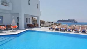 a swimming pool with chairs and a cruise ship in the background at Smy Bellevue Mykonos in Tourlos