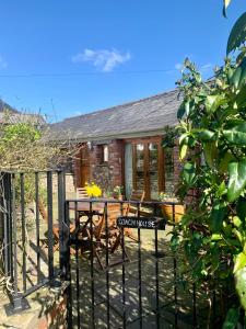 a cottage with a table and chairs in front of a fence at The Old Coach House in Pen-pergwm