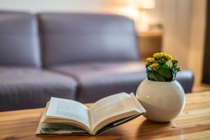 un libro y un jarrón con flores en una mesa en Vila Vipolže - Rooms & J. Suites en Vipolže