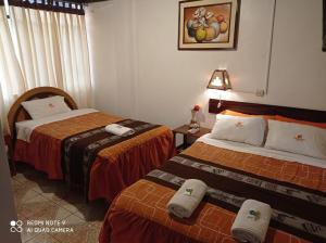 a hotel room with two beds and a lamp at DENNY'S MAPI in Machu Picchu