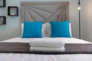 a bed with blue pillows and towels on it at Urban Oasis at Apex in Johannesburg