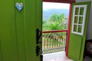uma porta verde que leva a uma varanda com vista em Pousada Vila Mineira em Lavras Novas