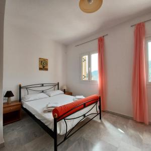 a bedroom with a bed and two windows with red curtains at Villa Syvros in Sívros +40 photos